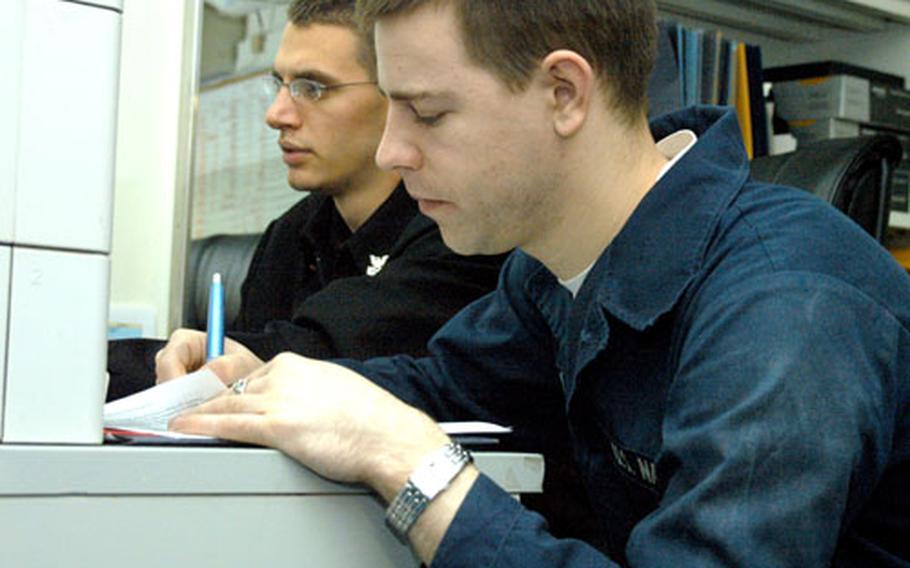 Navy seaman Robert Busch was one of more than 2,000 sailors who met with detailers aboard the USS Kitty Hawk last week to determine their next duty stations, or in the case of undesignated sailors, the schools that will determine their rates. Busch, 24, made out his dream sheet for detailer Petty Officer 1st Class Bryan Gill, rear, on Tuesday.