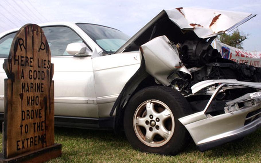 This wrecked car and fake tombstone on Camp Foster are one of many static displays parked at a gate on most of the military bases on Okinawa to remind people during the holiday season of the dangers of driving while impaired.