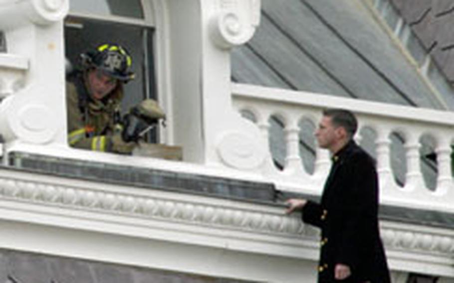 Firefighters talk to an unidentified man on a ledge outside the fifth-floor of the Eisenhower Executive Office Building on Wednesday. A fire there forced the evacuation of several hundred government workers.