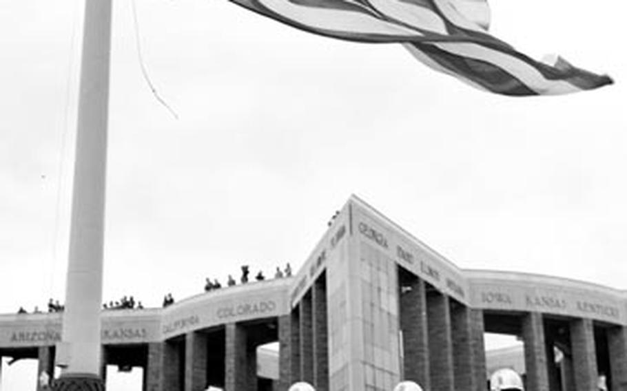 Members of the 1st Infantry Division honor guard present arms as the flag is raised during the dedication ceremony for a memorial honoring the Americans who lost their lives in the area during the World War II Battle of the Bulge.