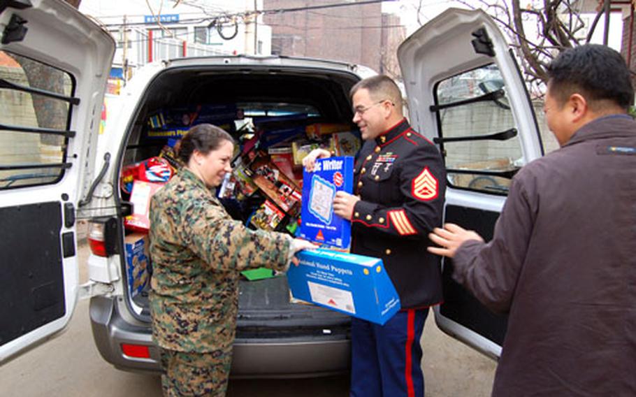 Gunnery Sgt. Marylyn Sabol and Staff Sgt. Nathan Natchke, Marine Forces Korea, unload toys at a Seoul-area orphanage Wednesday as part of the Toys For Tots program. Marines collected about 3,000 toys this year, most of which were donated to orphanages in South Korea.