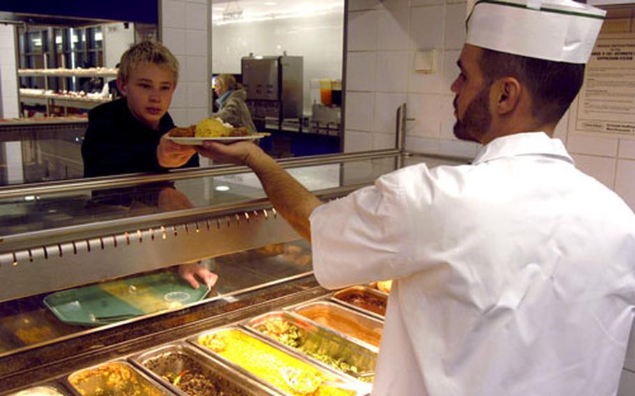 Mason Rawson, 12, son of Navy Cmdr. Lisa Rawson and Greg Rawson, receives a plate of Christmas chow from Frank Valdes, a cook at the Black Stallion Inn at Patch Barracks in Stuttgart, Germany.
