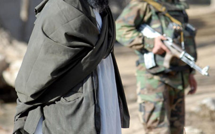 An Afghan man watches as soldiers from 1st Platoon, Company A, 1st Battalion, 4th Infantry Regiment soldiers pass in Mizan District, Afghanistan, in December. When not deployed, the 1-4 soldiers act as the opposing force that helps trains U.S. troops in Hohenfels, Germany.
