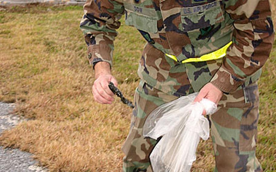 Maj. Jody Dow, 38, from Troy, Mont., with the 18th Logistics Readiness Squadron, picks up a piece of rubble along a runway.
