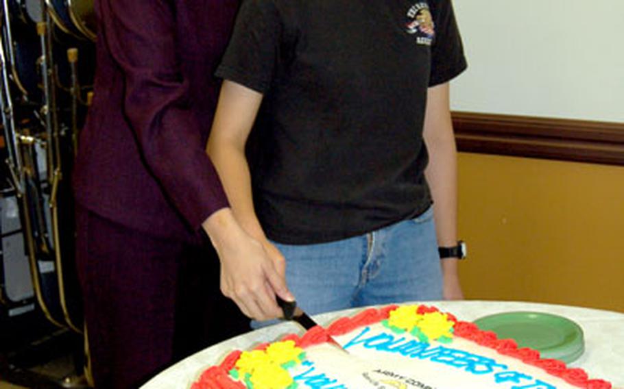 Volunteer of the quarter winners Myrna Loge, left, and Michelle Morgenstern participate in a cake-cutting at the end of the ceremony Friday at Yongsan Garrison.