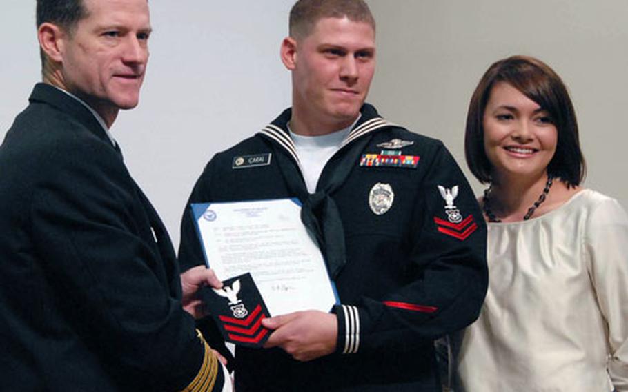 Petty Officer 1st Class John C. Caral is accompanied by his wife, Heather, while being awarded a meritorious advancement Tuesday by Sasebo Naval Base commander Capt. Tilghman Payne. Caral was promoted to petty officer first class for extraordinary combat service in Iraq during his deployment in 2006-2007.