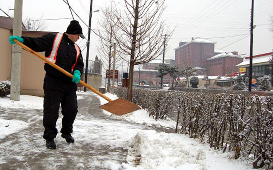 Yi Tong-hun, Department of Public Works, pushes snow off the sidewalks at U.S. Army Garrison Yongsan on Friday. The garrison received about 1/2 inch of snow, leading to six traffic accidents and the closure of two roads.