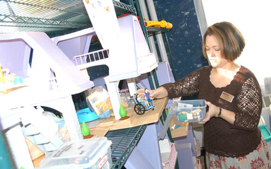 Lara Varcasia, the Family Child Care coordinator at Misawa Air Base, Japan, stands next to a shelf of doll houses among toys and other supplies that licensed Family Child Care providers can borrow for their homes. The base needs more in-home providers. Mandatory training starts Monday for anyone interested in getting licensed.
