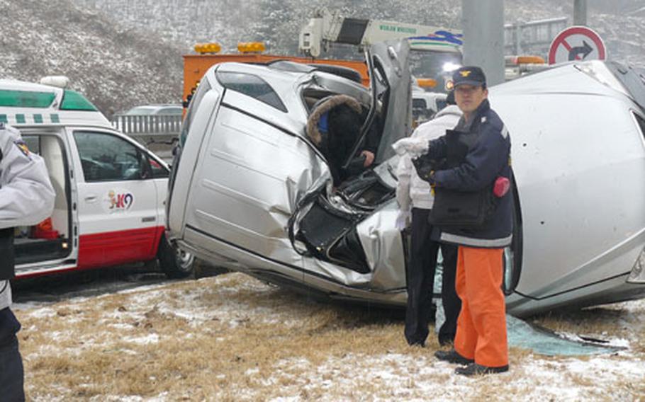 South Korean rescue personnel work on a vehicle that smashed into a telephone pole on a highway near Camp Eagle on Jan. 11. Two U.S. soldiers, Staff Sgt. Kimberly Veal and Pfc. Bradley Herron, assisted the injured South Koreans after coming across the site while returning to their camp.