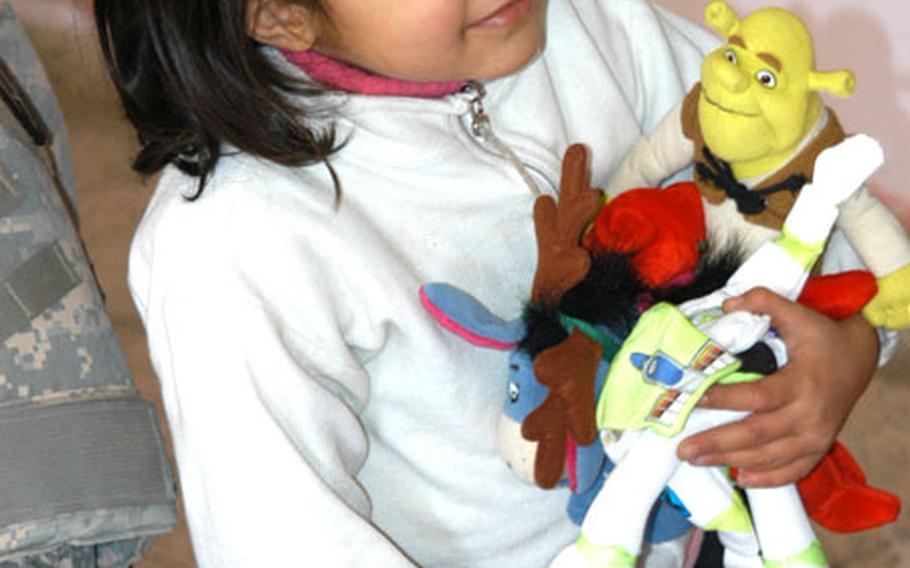 An Iraqi girl cradles the toys she received Tuesday from U.S. soldiers and local police at a school in Khadra.