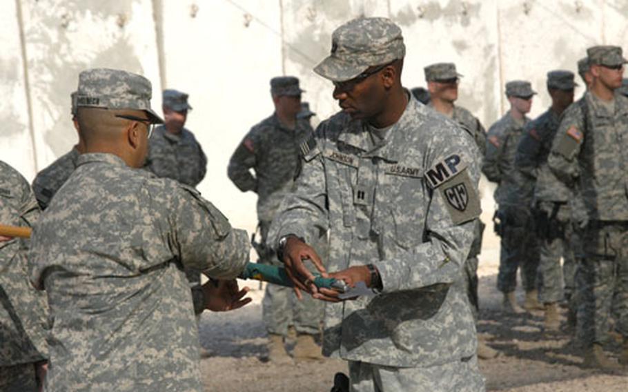 First Sgt. Ramon Domenech, 46, left, of Puerto Rico, and Capt. Darren Johnson, 37, of Tuscaloosa, Ala., case the 127th Military Police Company's guidon Saturday during a transfer of authority ceremony at Forward Operating Base, Kalsu, Iraq. Johnson is the company commander, while Domenech serves as its first sergeant.