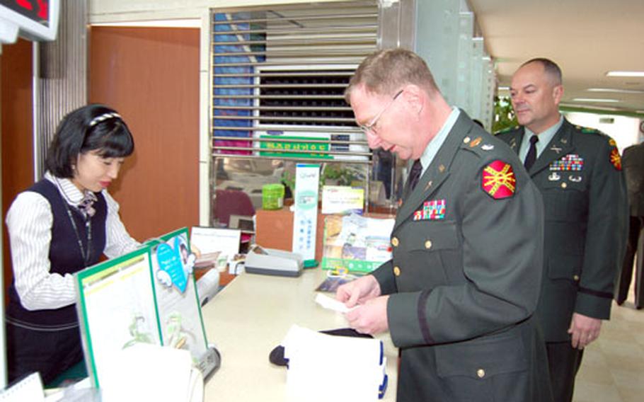 U.S. Army Garrison Yongsan command chaplain Lt. Col. James King deposits money donated by the U.S. military community to victims of a Dec. 7 oil spill Wednesday at a NongHyup Bank in Taean, while commander Col. Dave Hall looks on. The money, donated through chapels at USAGY and U.S. Army Garrison Red Cloud, totaled about $17,000.