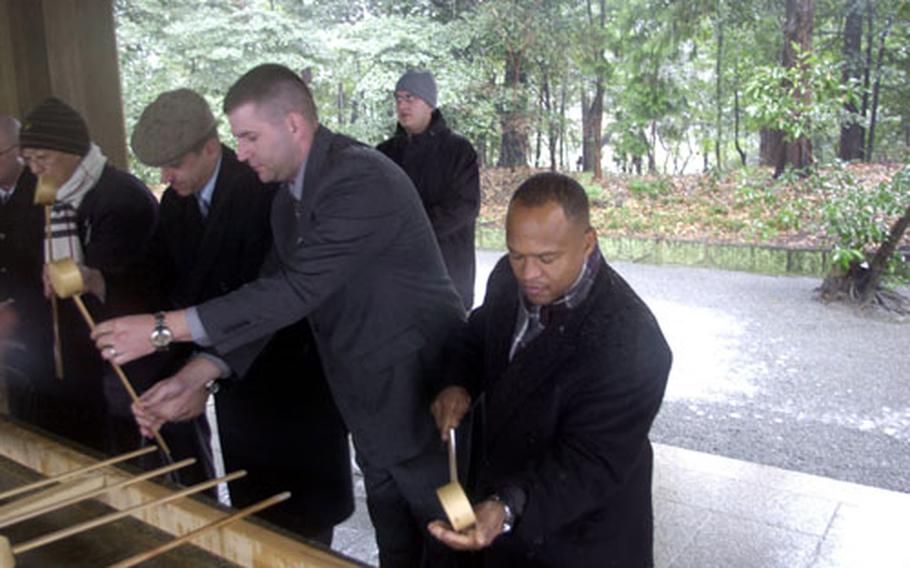 Army Maj. Glenn Simpkins, right, G-8 deputy chief of staff from Camp Zama, and other U.S. Forces Japan officers wash their hands before entering the Meiji Shrine in Tokyo on Wednesday.
