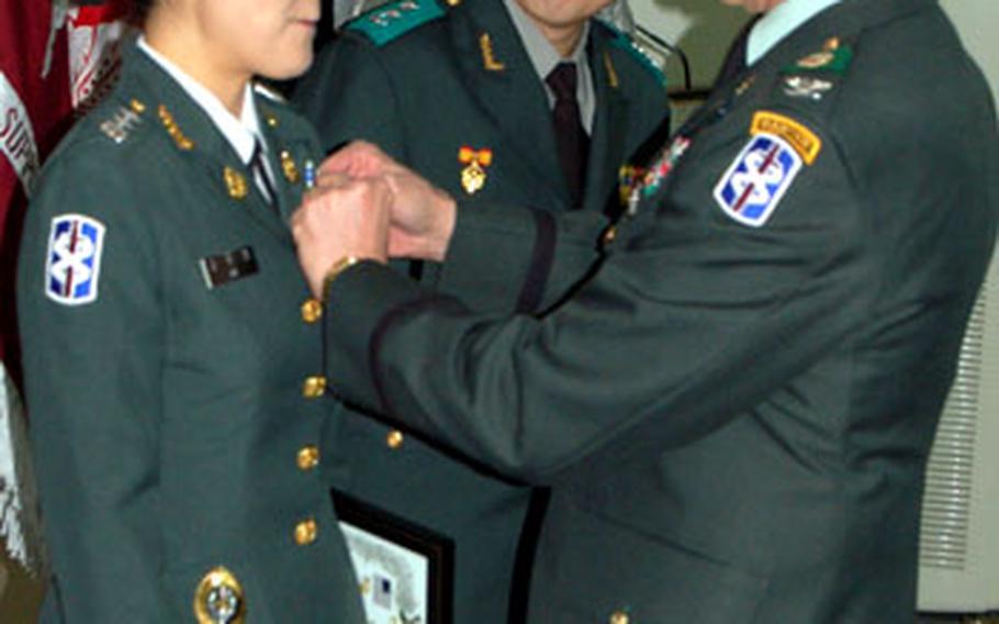 Col. James Jolissaint, 18th Medical Command commander, pins an Army Achievement Medal on South Korean army Capt. Kim Hee-jeong on Friday during a graduation ceremony for participants in the Integrated Service of Republic of Korea Military Health Care Personnel Program.