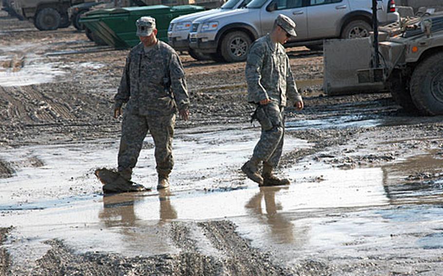 Two U.S. soldiers wade through a wet, muddy parking lot Friday afternoon at Camp Liberty, Iraq. Last week's rainfall brought mucky, sloppy conditions back to most areas across the country.