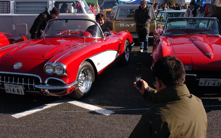 Japanese visitors take photos of a 1959 convertible Corvette displayed alongside a 1966 Stingray Corvette at the Classic Car Festival New Year Meeting, hosted by Japan Classic Car Association, held in Odaiba on Sunday.