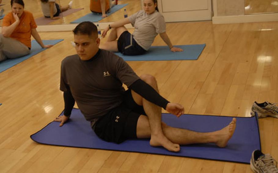 Senior Airman James Lopez stretches his back with a spinal twist during a yoga class at RAF Mildenhall. Lopez started taking yoga a few weeks ago.