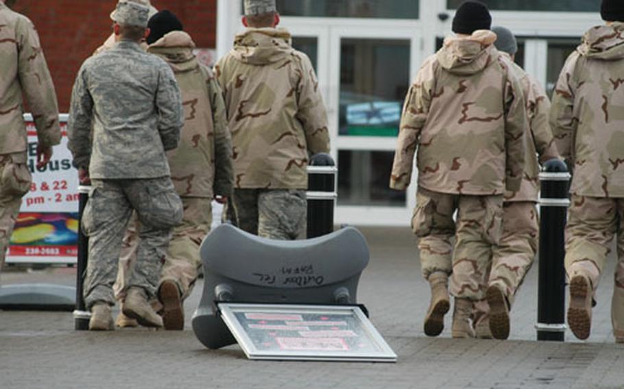 A group of airmen walk past a sign blown down by strong gusts in front of RAF Mildenhall&#39;s BXtra. Gale-force winds hit the base Thursday, causing disruptions in its flight operations.