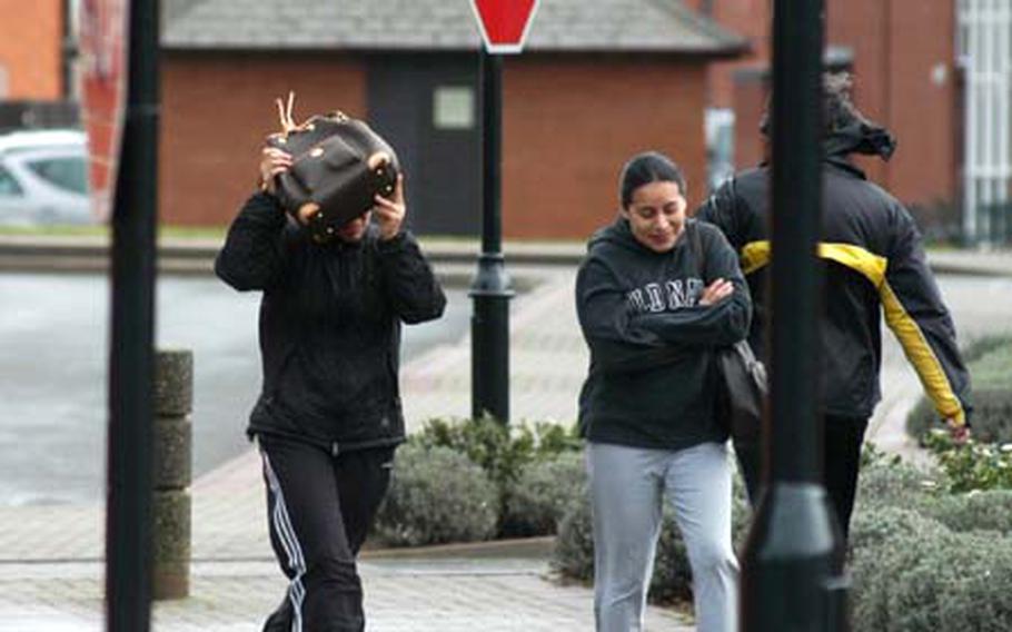 Military spouse Betty Gonzalez, left, uses her purse to shield her face from chilly wind gusts while walking with Jeimmy Martinez, also a spouse, to RAF Mildenhall&#39;s BXtra.