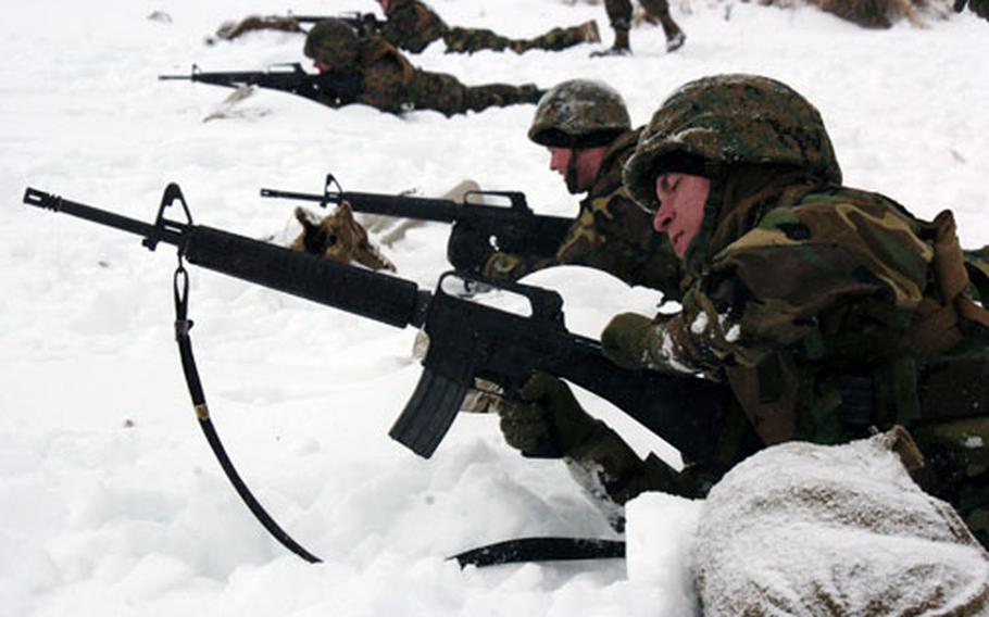 Lance Cpl. Daryl Stroop loads an M-16 rifle with ammunition while lying in the snow during practice maneuvers Wednesday at Camp Fuji, Japan.