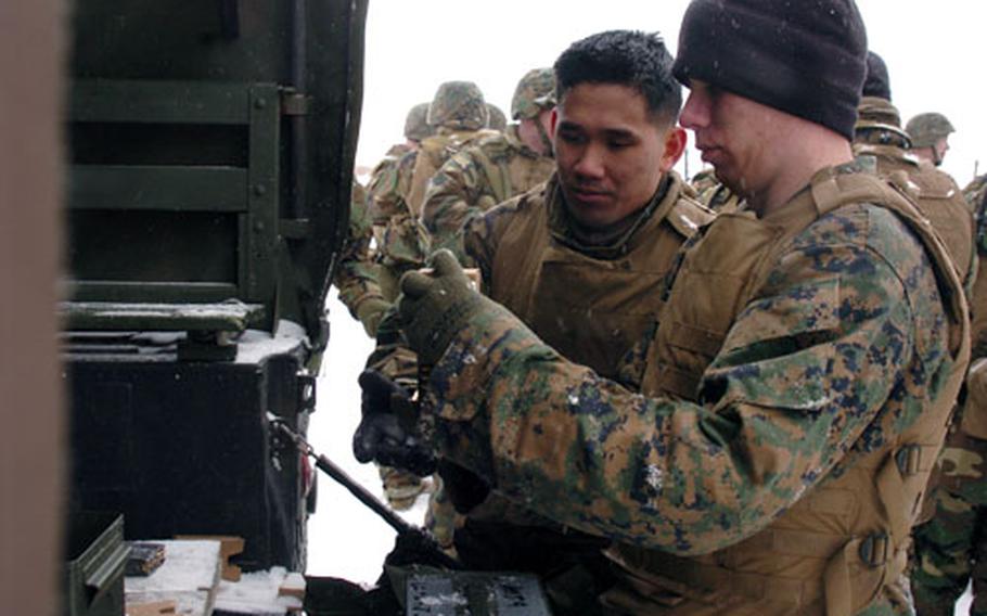 From left, Lance Cpl. Legrand Golden and Lance Cpl. Cason Hawley hand out clips of ammunition during maneuvering exercises Wednesday at Camp Fuji, Japan.