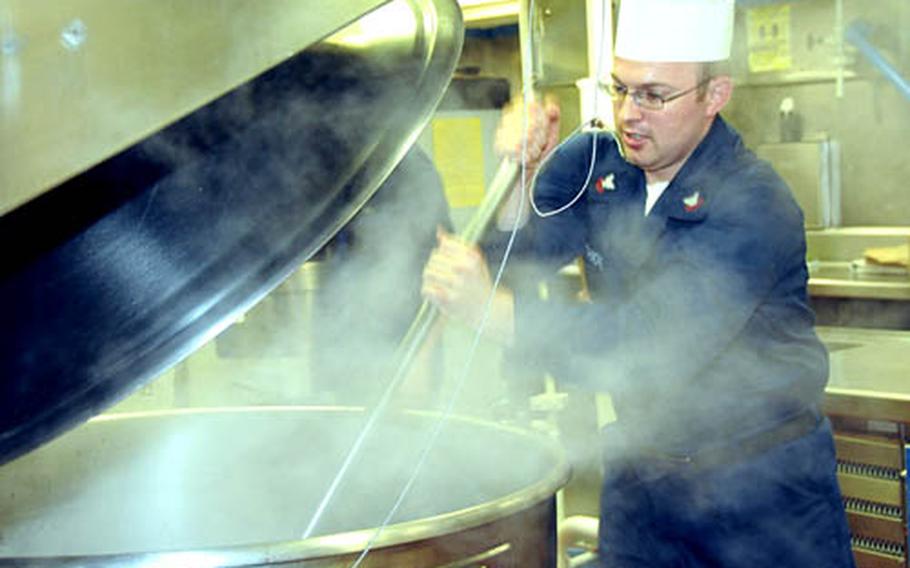 Petty Officer 2nd Class Ryan Briggs, 24, a cook on the USS Essex, stirs a vat of beef stroganoff that was to be one of the main courses for dinner Tuesday evening aboard the ship. Briggs is so used to cooking in servings of 800 or more that he now finds "it hard to cook small portions," he said, so he winds up inviting 20 or so people to his home "so I can cook properly."