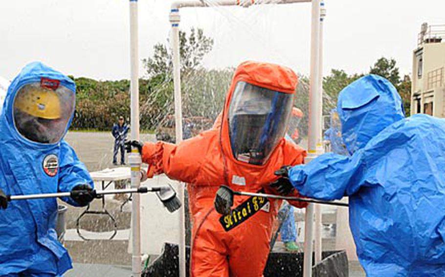 Kadena Air Base, Okinawa, firefighters, in the blue hazerdous-material protection suits, decontaminate a Nirai firefighter during a joint training exercise Thursday.