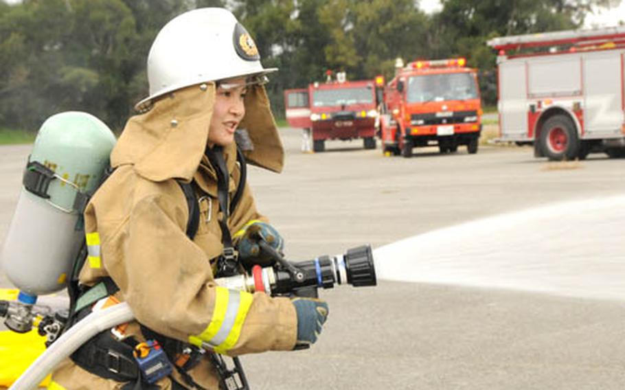 Yuki Uechi, 25, a firefighter with the Nirai Fire Department, sprays water on two other firefighters to decontaminate them during a joint hazerdous-material training exercise. Water can be used to decontaminate about 90 percent of hazerdous materials, according to Chief Master Sgt. Rodolfo Gonzales, Kadena&#39;s fire chief.