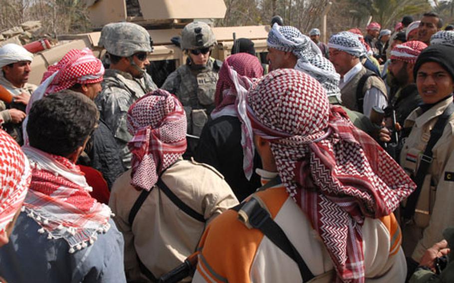 Iraqi volunteers, part of the U.S.-funded “Sons of Iraq,” crowd Army Capt. William Clark, 32, of Wheeling, Ill., during clearing operations south of Salman Pak in Iraq.