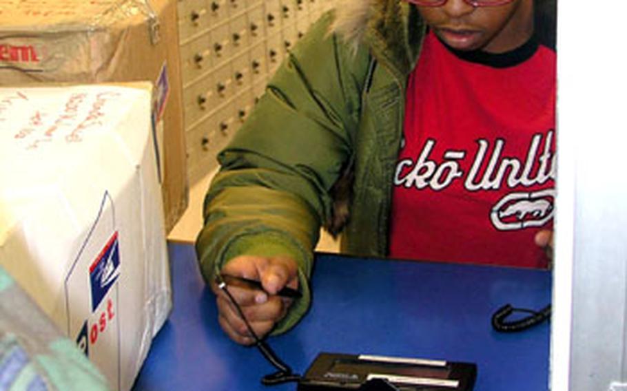 A customer signs for a parcel using a digital signature pad at the Osan Air Base post office in South Korea on Friday.
