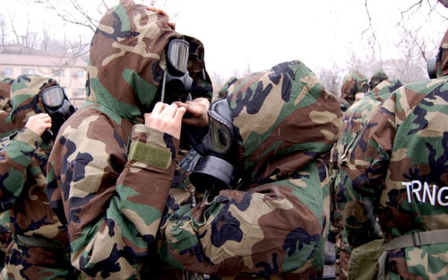 Soldiers at Yongsan Garrison, South Korea, help each other don chemical protective gear during a training Feb. 27, 2008.
