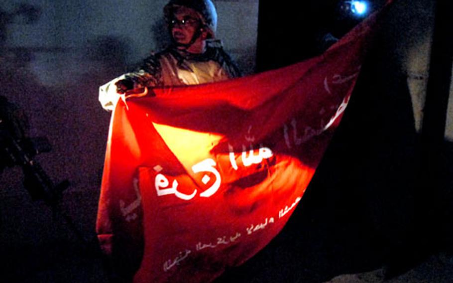 John Issa, an interpreter who’s an American citizen originally from Lebanon, translates words on a Shiite flag found Monday night in the Hurriyah area of Baghdad in a home once used as a kidnappers’ hide-out. The flag reads, “Muqtada Sadr, savior of god,” a reference to the Shiite cleric who heads the Mahdi Army. Al-Sadr has asked his followers to march from Baghdad to Najaf on Wednesday.