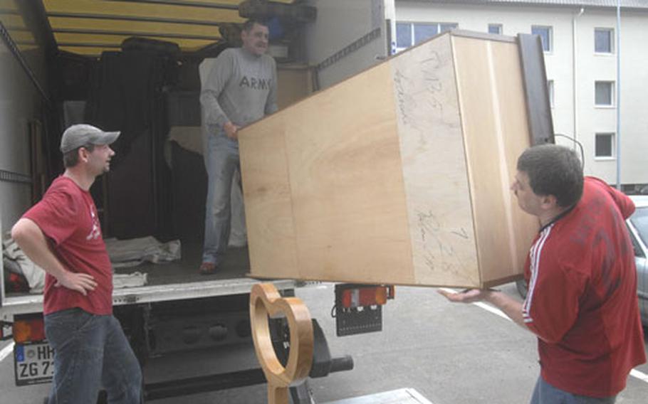 German movers Marcus Clemens, right, and Udo Kiktenko guide a piece of Army Sgt. Melisa Hall’s furniture onto a moving truck Thursday as fellow mover Mario Leonhard catches his breath. Hall is one of 77 families in housing on the Landstuhl Regional Medical Center post that are being forced to move out of eight buildings to make way for incoming reservists.