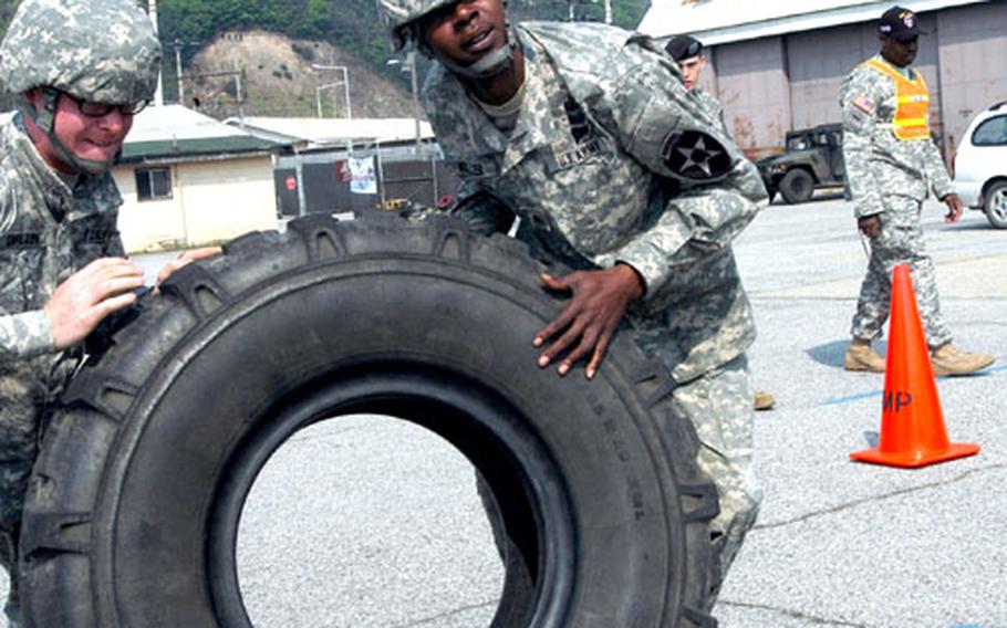 Pvt. Ian Carlson, of Milnor, N.D., and Sgt. Eric Miller of Jacksonville, Fla., flip a giant tire toward a Palletized Loading System vehicle Thursday. The tire flip and change was one of 13 events in the 302nd Brigade Support Battalion's annual Truck Rodeo.