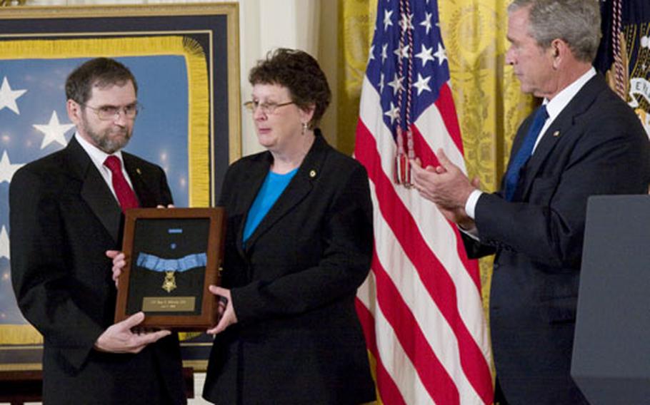 President Bush applauds as Tom and Romayne McGinnis display their late son's Medal of Honor Monday at the White House.