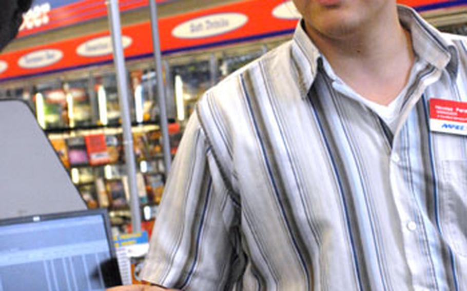 Nicolas Persijn, an employeed at the Pulaski Barracks shopette in Kaiserslautern, Germany, hands a new Army and Air Force Exchange Service fuel card to an unidentified customer.
