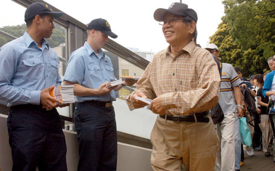 Yokosuka sailors Seaman Michael Leak, left, and Petty Officer 1st Class Mike Ahrendt, center, passed out free copies of "CVN 73," a Navy-created manga about the USS George Washington, the aircraft carrier scheduled to replace USS Kitty Hawk in Yokosuka.