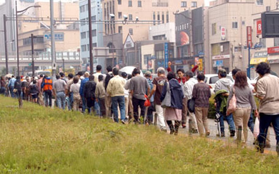 The line for the manga about the USS George Washington stretched down the road in front of Yokosuka Naval Base on Sunday. Officials estimated they distributed about 800 copies of the Japanese comic.
