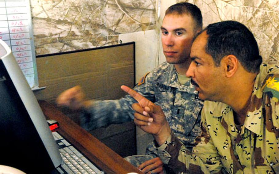 First Lt. John Rebolj shows photos found in a weapons cache to Capt. Mahmud Masin Muhammad, a battalion intelligence officer. Rebolj, the Blue Platoon leader for Company M, 3rd Squadron, 3rd Armored Cavalry Regiment, hoped Muhammad could identify some of the men in the photos.