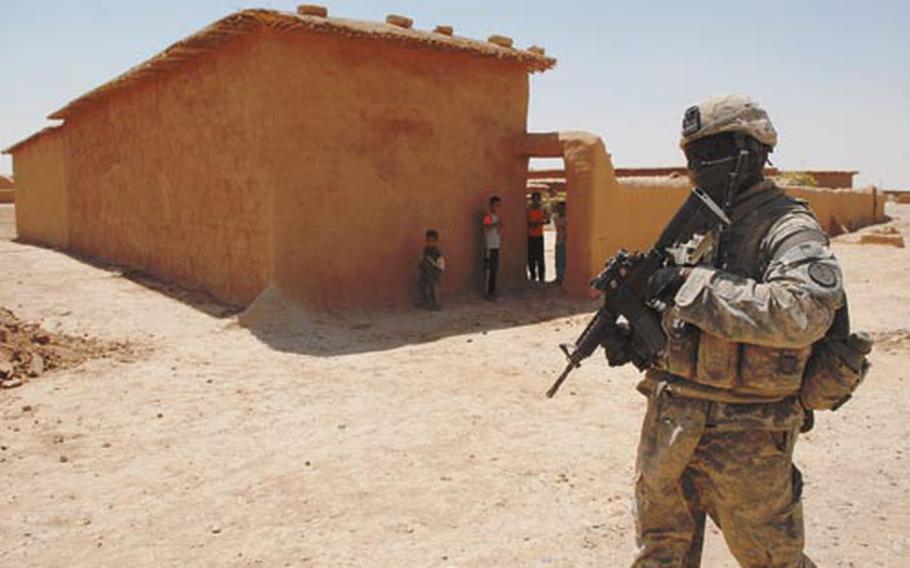 Iraqi children watch Sgt. Brandon Mines – a soldier in Troop A, 1st Squadron, 3rd Armored Cavalry Brigade – during a visit the Americans made Wednesday to Mustantiq, Iraq. Like other small towns, Mustantiq is a collection of mud homes surrounded by a waterless area with few resources.