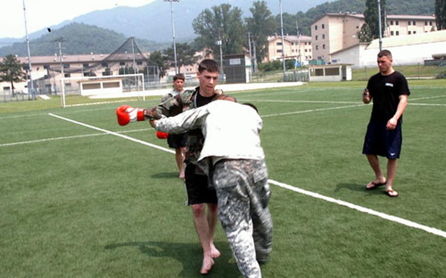 Spc. Joshua Reid, standing, of the 2nd Infantry Division's 2nd Battalion, 9th Infantry, spars with Pvt. Johnny Herrera at Soldier Field on Camp Casey on Friday. The field showed elevated levels of lead but remained within safety limits, military officials said Friday. A field at Camp Henry closed due to higher lead levels.