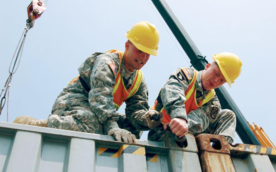 Pfc. Malcolm Crawford, left, and Spc. James Allgood, 551st Inland Cargo Transfer Company, prepare a 60,000-pound cargo container for movement onto a truck during rail operations Friday at Yongsan Garrison. The containers were shipped via rail to Yongsan to avoid delays that might be caused by the truckers’ strike that had much of the cargo entering South Korea stranded at the port.