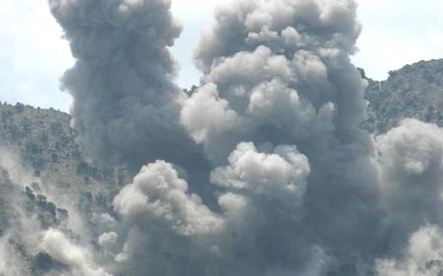 A Kiowa Warrior helicopter flies over billowing clouds of smoke and debris raised by two bombs dropped by a B-1 bomber Saturday near the village of Tut Naw in northeastern Afghanistan. Three Afghan army soldiers and at least seven insurgents were killed in a gun battle Saturday in the valley above the village that’s close to the Pakistan border.