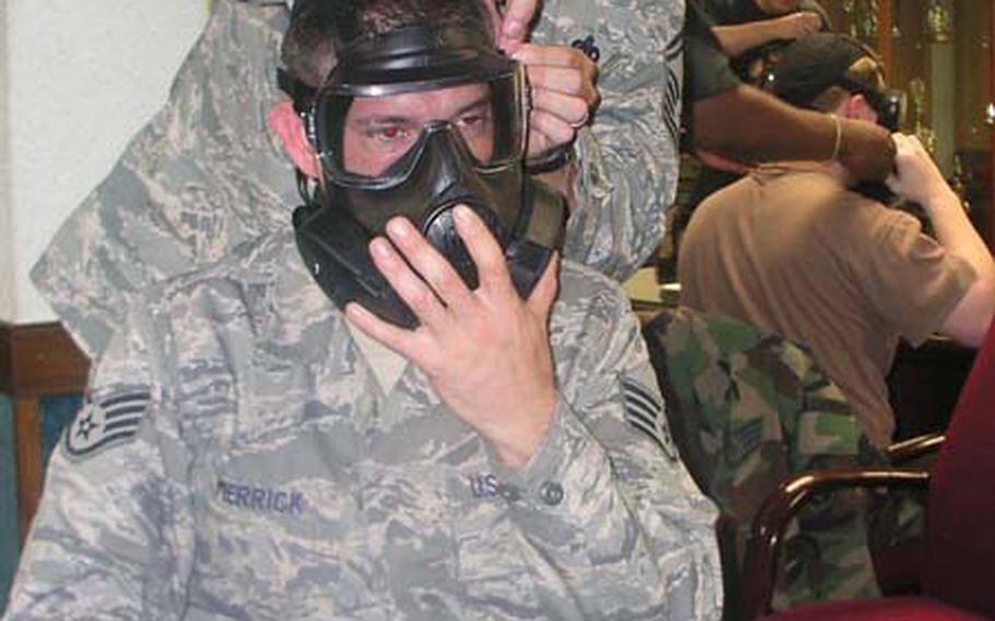 At Osan Air Base in South Korea on Friday, airmen help each other fit the U.S. military’s new joint M-50 protective mask during an instructional session on its fitting and use.