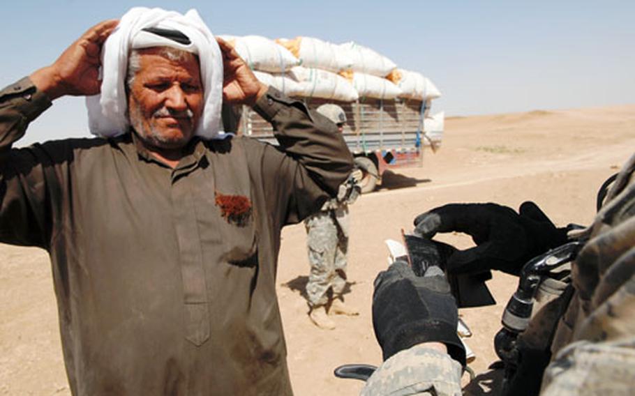 An Iraqi man who was in a semi carrying bags of sugar near a suspicious gas tank Tuesday waits for U.S. soldiers to search him and his truck near Buwayr. Bomb squad GIs exploded the tank, which turned out to be empty.
