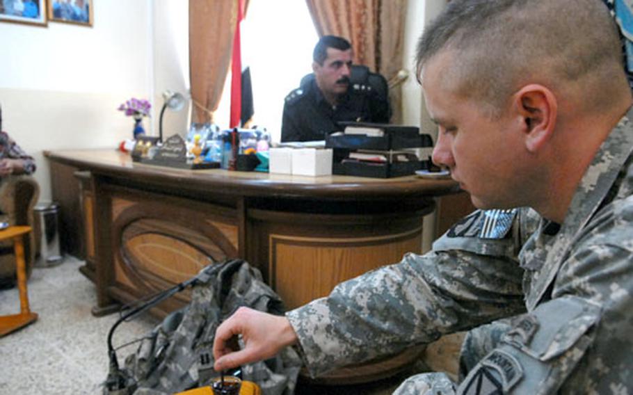 Capt. Doug Serie stirs a cup of tea during a meeting Monday with Police Col. Bestoon Mohammad Qadir (in background), the police chief in charge of Kirkuk’s Azadi district. Serie, who commands Headquarters and Headquarters Company, 2nd Battalion, 22nd Infantry Regiment, works extensively with Iraqi police in Kirkuk’s eight police districts.