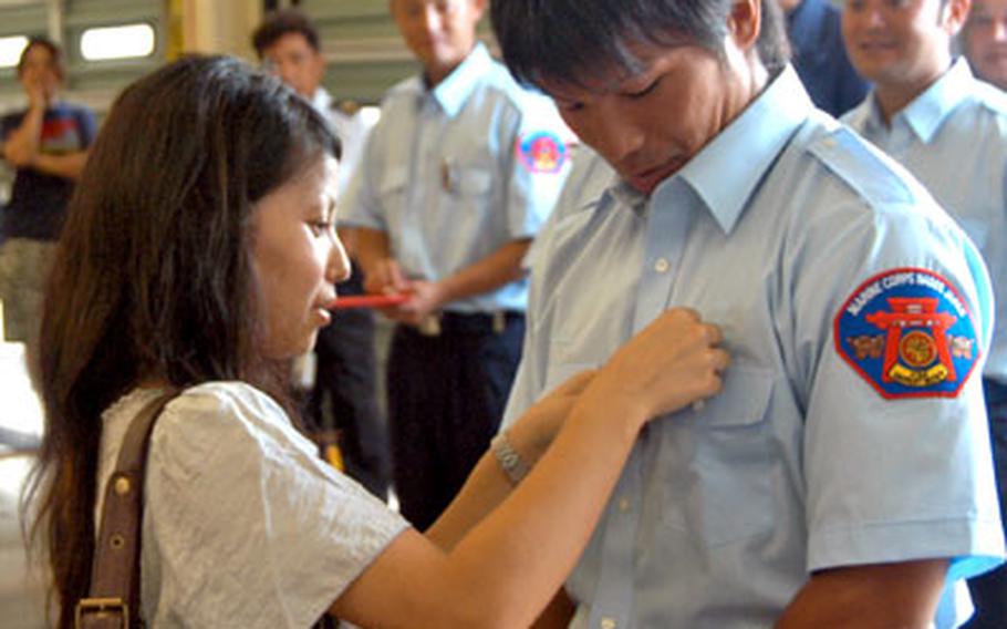 Yuki Harata is pinned by his wife, Nao, at his fire academy graduation ceremony Monday at Camp Foster. Each cadet was presented with a badge, name plate and a certificate.