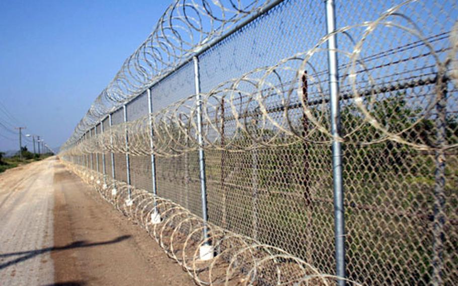 Three rows of barbed wire line the fence between U.S. Naval Station Guantanamo Bay and Cuba. The land immediately on the other side is a buffer zone between the U.S. fence and the Cuban fence.