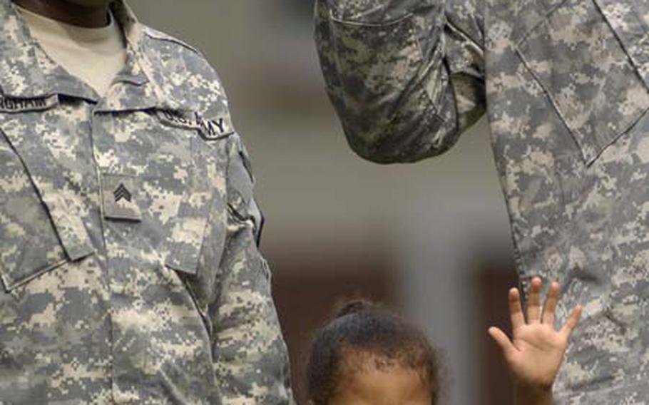 Delora Wymer, 4, raises her hand along with Sgt. Fiona Cunningham, a soldier assigned to Headquarters and Headquarters Detachment, 39th Transportation Battalion, as 13 soldiers and one recruit take an oath of enlistment Thursday during a retreat ceremony at Panzer Kaserne. Delora's mom, Spc. Norica Wymer from the 147th Postal Company, and Cunningham were among those reenlisting in the ceremony.
