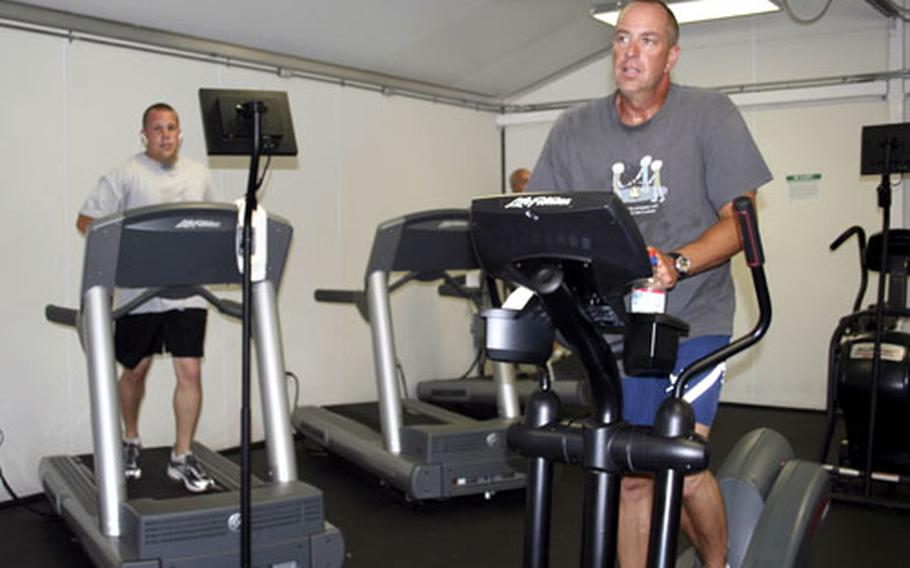 Air Force Chief Master Sgt. Gerry Tembrock, right, works out in the cardio room at D.J. Denich Gym at Guantanamo Bay, Cuba. Though the naval station can feel isolated at times, Tembrock said three months into his six month tour he's reconnected with himself.